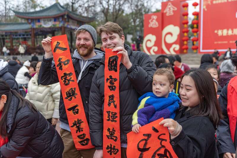 几名外国游客在活动现场展示书写的春联和福字